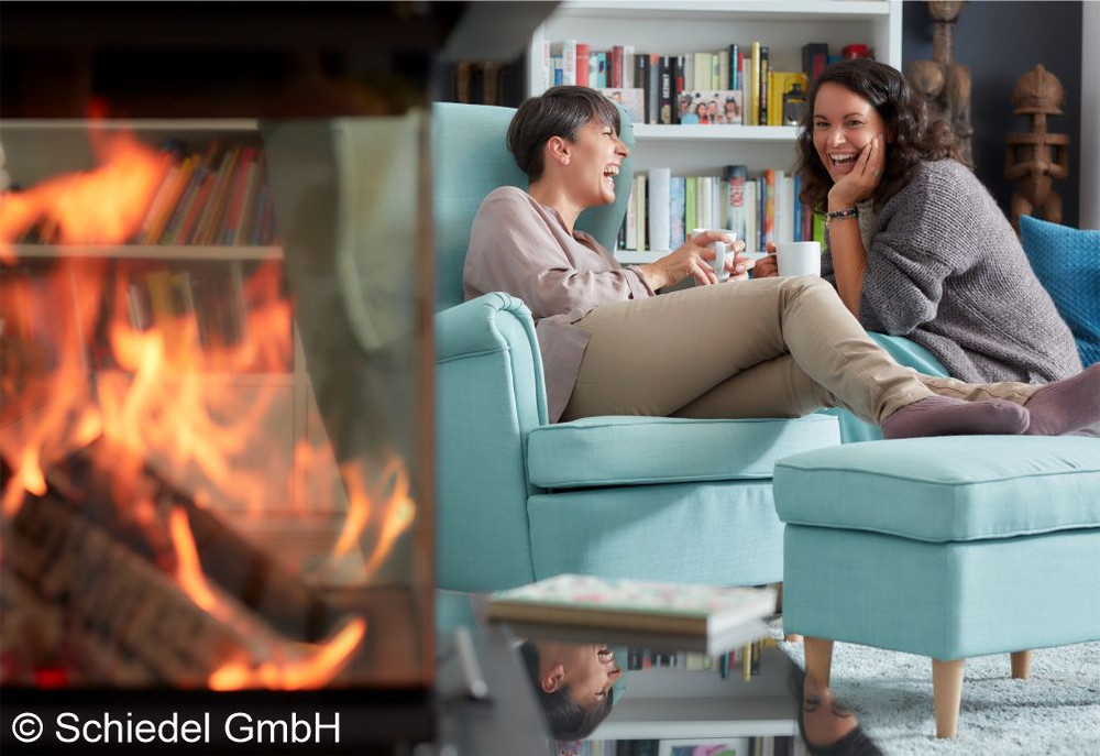 Zwei Frauen sitzen auf einer Couch neben dem Kamin
